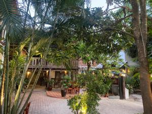 a courtyard with palm trees and tables and a building at Golden Sun Hotel Luang Prabang in Luang Prabang