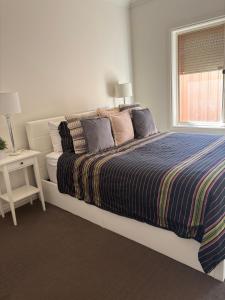 a bedroom with a bed with a striped blanket and a window at Private, Central, Sunny Guest Room in Welcoming Home in Campbelltown +4 photos