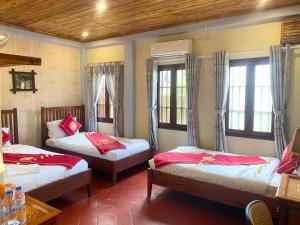 a room with three beds and two windows at Golden Sun Hotel Luang Prabang in Luang Prabang