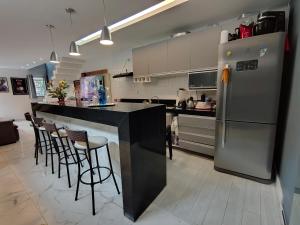 a kitchen with a refrigerator and some bar stools at Casa 2 Suítes Aluguel COP 30 Belém Pará in Belém +9 photos