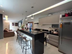 a kitchen with a counter and bar with stools at Casa 2 Suítes Aluguel COP 30 Belém Pará in Belém