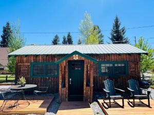 a cabin with a green door and chairs on a deck at The Loose Moose Cabin #11 At Downtown Grand Lake in Grand Lake