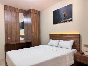 a bedroom with a large bed with a wooden headboard at El Bakatir Homestay By Akasha in Banyuwangi