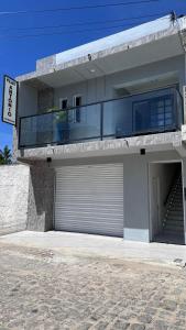 a white house with a garage and a balcony at Flat Antônio in São José do Egito