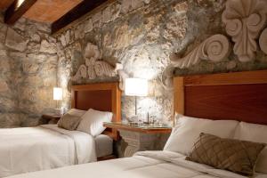 a bedroom with two beds and a stone wall at Casa Serdán, Suites & Events in Morelia +109 photos
