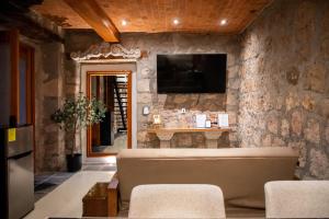 a living room with a couch and a tv on a stone wall at Casa Serdán, Suites & Events in Morelia