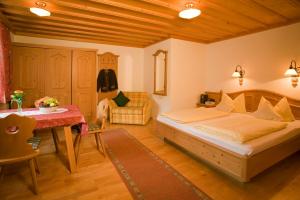 a bedroom with a bed and a table and a chair at Pension Breitenlohner in Reit im Winkl