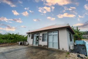 una pequeña casa blanca con un cielo nublado en 夏風-なつバル-, en Isla Miyako