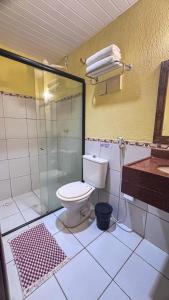 a bathroom with a toilet and a glass shower at Vilamar Suítes in Aquiraz