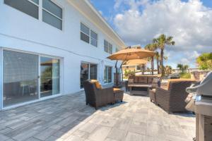 a patio with chairs and an umbrella next to a building at Sea La Vie Beach Oceanfront Patio Pet Friendly in Jacksonville Beach