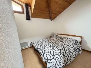 a bedroom with a bed with a black and white comforter at Maison calme proche plage et commerces - FR-1-831-13 in Biscarrosse
