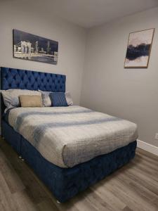 a bed in a bedroom with a blue headboard at 2 bedroom basement-All Incl in Fort McMurray
