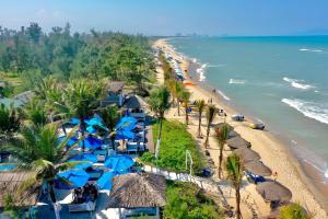 eine Luftansicht auf einen Strand mit blauen Sonnenschirmen in der Unterkunft Ancient Garden Boutique Hoi An in Hoi An