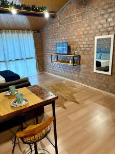 a living room with a table and a brick wall at Pousada Refúgio das Águas Quarto 3 in Chapecó