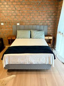 a bed in a room with a brick wall at Pousada Refúgio das Águas Quarto 3 in Chapecó