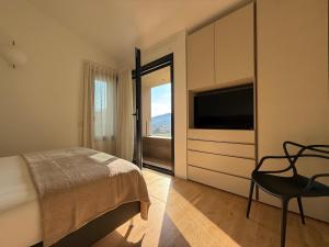 a bedroom with a bed and a television and a chair at Exclusive Villa Perla & swimming pool in Bovezzo +94 photos