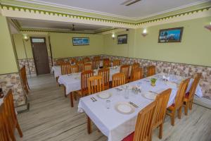 a dining room with white tables and wooden chairs at Divyaraa Breathing Stone in Kalimpong