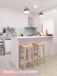 una cucina con bancone bianco e 2 sgabelli di 荷風緩緩包棟民宿 a Jiaoxi