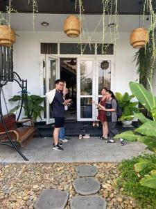 un groupe de personnes debout à l'extérieur d'une maison dans l'établissement T'Homestay garden villa, à Thôn Lại Thê 1 autre photo