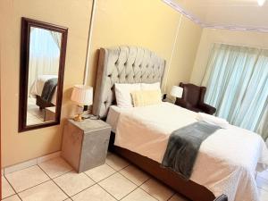 a bedroom with a bed and a mirror and a chair at Whizzy lifestyle lodge in Duvhapark