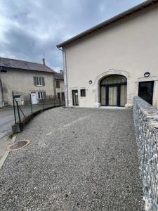 a white building with a fence next to a street at Appartement proche du lac de Vouglans in Charchilla