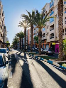 a street with palm trees and cars parked on it at Charming duplex with pool in Torrevieja +20 photos