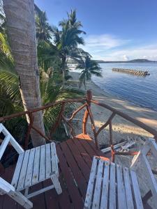 a bench sitting on the beach next to the water at Destiny Rainbow Beach Resort in Siquijor