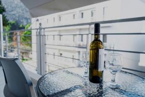 a bottle of wine sitting on a table with two glasses at Marietta City Center Apartment Nafplio Near Old Town & Arvanitia Beach in Nafplio
