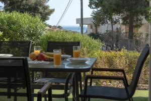 Palm & Pearl Apartment في أثينا: طاولة مع صحن من الفاكهة وأكواب من عصير البرتقال