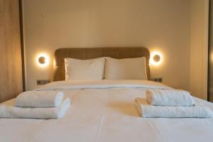 Palm & Pearl Apartment في أثينا: سرير ابيض كبير عليه منشفتين