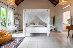 Moon & Honey villa في أوبود: غرفة نوم بسرير أبيض مع مظلة