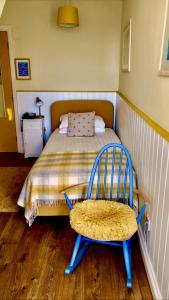 a bed with a blue chair in a bedroom at No: 1 The Esplanade Guest Accommodation. in Tenby +10 photos