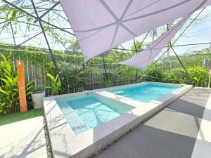 a swimming pool with an umbrella on a patio at The Ten Poolvilla Huahin in Hua Hin