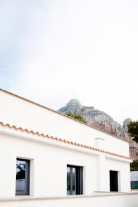 a white building with windows and mountains in the background at Monte Monaco B&B in San Vito lo Capo