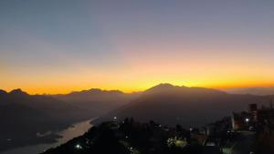 a sunset over a city with a river and mountains at Hotel bhagirathi darshan in Jāmb