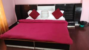 a large bed with red and white pillows on it at Hotel bhagirathi darshan in Jāmb