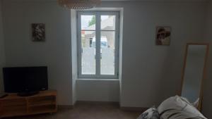 a living room with a tv and a window at chez Marie et Xav in Frasne-les-Meulières +6 photos