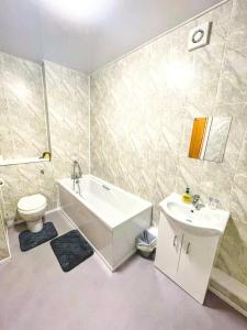 a bathroom with a tub and a toilet and a sink at Top Floor Apt Promenade Sea Views Sleeps 6 Shore Vibes in Morecambe