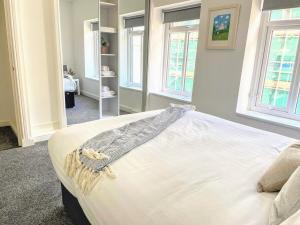 a large white bed in a room with windows at Top Floor Apt Promenade Sea Views Sleeps 6 Shore Vibes in Morecambe