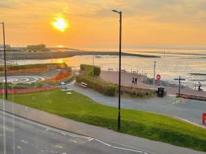 a sunset over a street with a beach and the ocean at Top Floor Apt Promenade Sea Views Sleeps 6 Shore Vibes in Morecambe