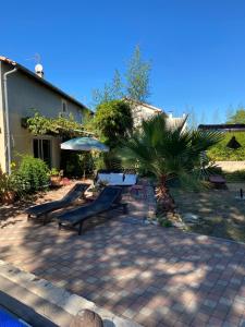 een terras met banken, een tafel en een parasol bij Belle suite Un petit voyage au calme à 10 mnCV de Béziers entrée indépendante in Béziers
