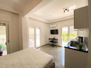 a bedroom with a bed and a kitchen with a sink at Hakan's Seaside Apartments in Nea Kalikratia