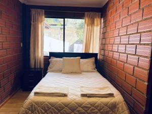 a bed in a room with a brick wall at Casa Brisa Volcánica in Baños