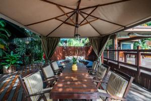 a wooden table and chairs on a deck with an umbrella at Luxury Tented Village @ Urban Glamping in St Lucia