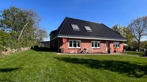a small red brick house with a grass yard at Ferienwohnung Sonne & Sauna in Sönnebüll