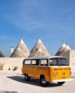 a yellow van parked in front of some pyramids at Trulli Fortunato private, heated swimming pool in Locorotondo