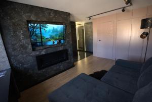a living room with a couch and a tv on a wall at Black Pearl Luxury Apartment in Ventspils