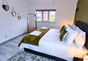 a bedroom with a large bed with white sheets and green pillows at 3-Bedroom Leeds Beach Home - 8 minutes to City Centre, Free Private Parking for 2 Cars, 70" Smart TV, Projectors in Bedrooms, Free WiFi - Ideal for Family and Contractors in Killingbeck