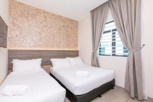 two beds in a small room with a window at E Hotel Kulim in Kulim