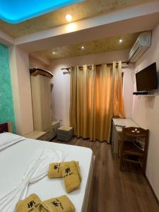 a bedroom with a bed and a desk and a television at Hotel Besa in Shëngjin